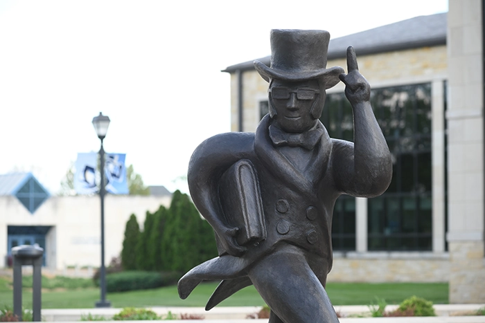 Bronze Ichabod statue tips its hat while holding a book outside Morgan Hall on the Washburn campus.